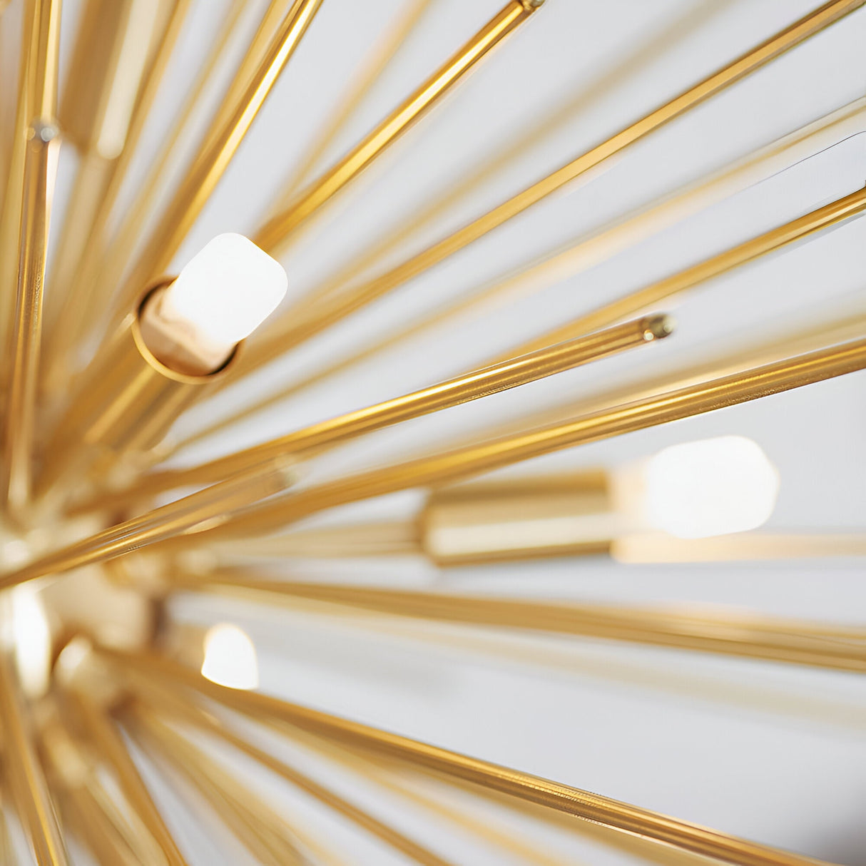 Close-up of the Merrick 9 Light Sputnik Pendant in satin brass, showing star-burst metal rods radiating from the centre with small G9 bulb tips against a plain light background.