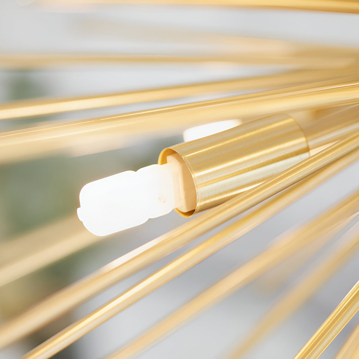 Close-up of the Merrick 9 Light Sputnik Pendant in satin brass, showing one rod's brushed metal socket with a lit G9 bulb amid radiating arms.