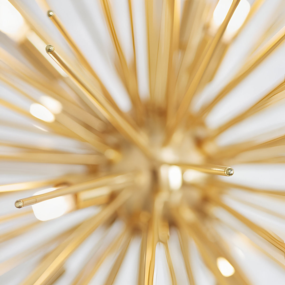 Close-up of the Merrick 9 Light Sputnik Pendant, satin brass rods radiating from a central hub with small G9 bulb tips, set against a plain white background.