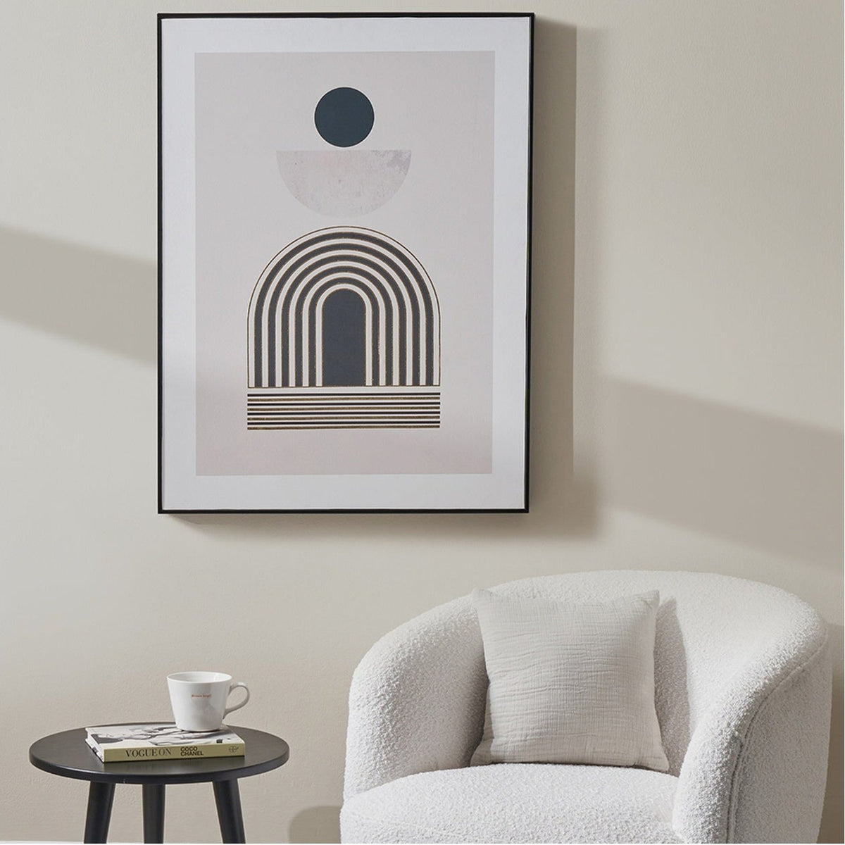 Framed Art Deco print, 60 x 80cm, featuring a black arch, sun and half-moon design, displayed above a boucle armchair in a neutral living room.