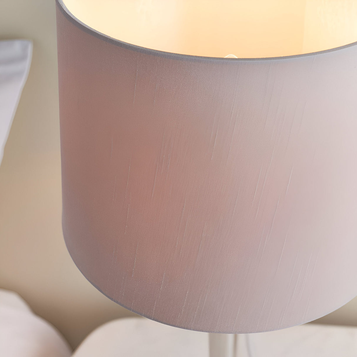 Close-up of the Endon Crandale table lamp's mink faux silk drum shade, illuminated to show its warm glow against a soft neutral interior.