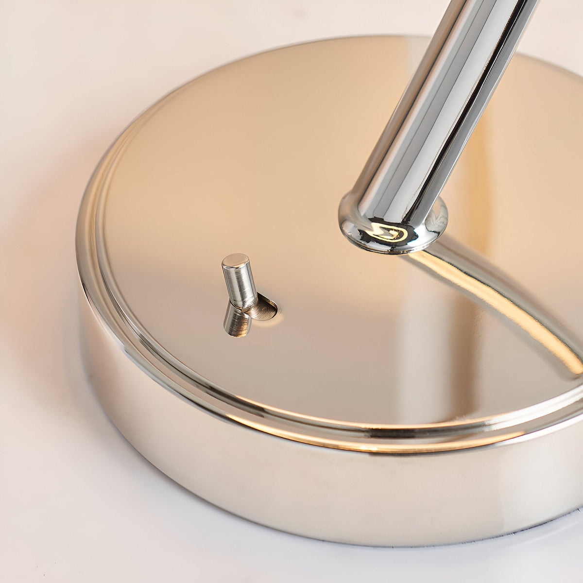 Close-up of the Brockfield Table Lamp's round nickel base with curved metal stem and small toggle switch, shown on a plain light background.