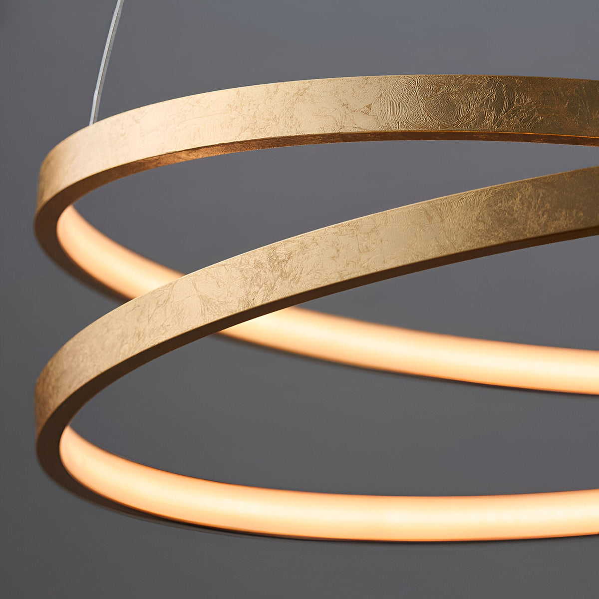 Close-up of the Endon Cliffley ring pendant showing its gold leaf finished metal hoop with integrated LED glowing warmly along the inner edge.