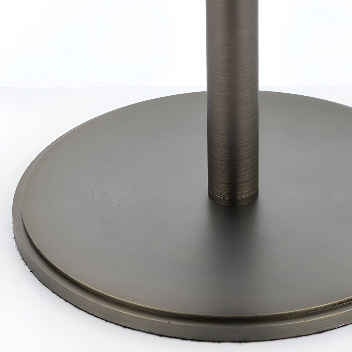 Close-up of the Brendon Table Lamp's round metal base and stem in a brushed bronze finish, shown against a plain white background.