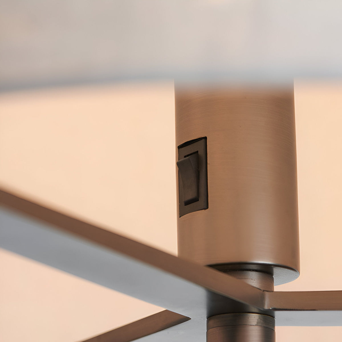 Close-up of the Endon Brendon floor lamp's brushed bronze lamp holder with rocker switch and slim metal frame supporting a natural linen shade.