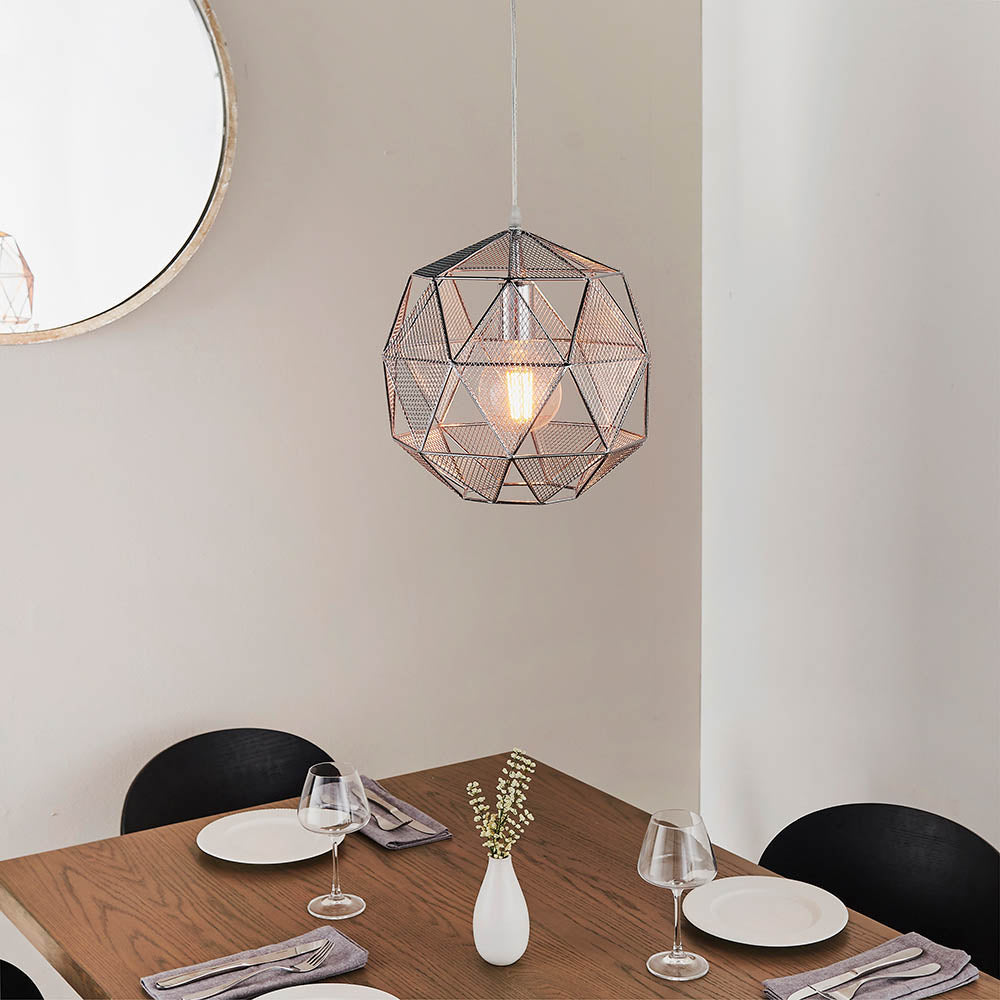 Aldford Pendant in polished chrome, a geometric wire-frame globe shade with exposed bulb, hanging above a wooden dining table.