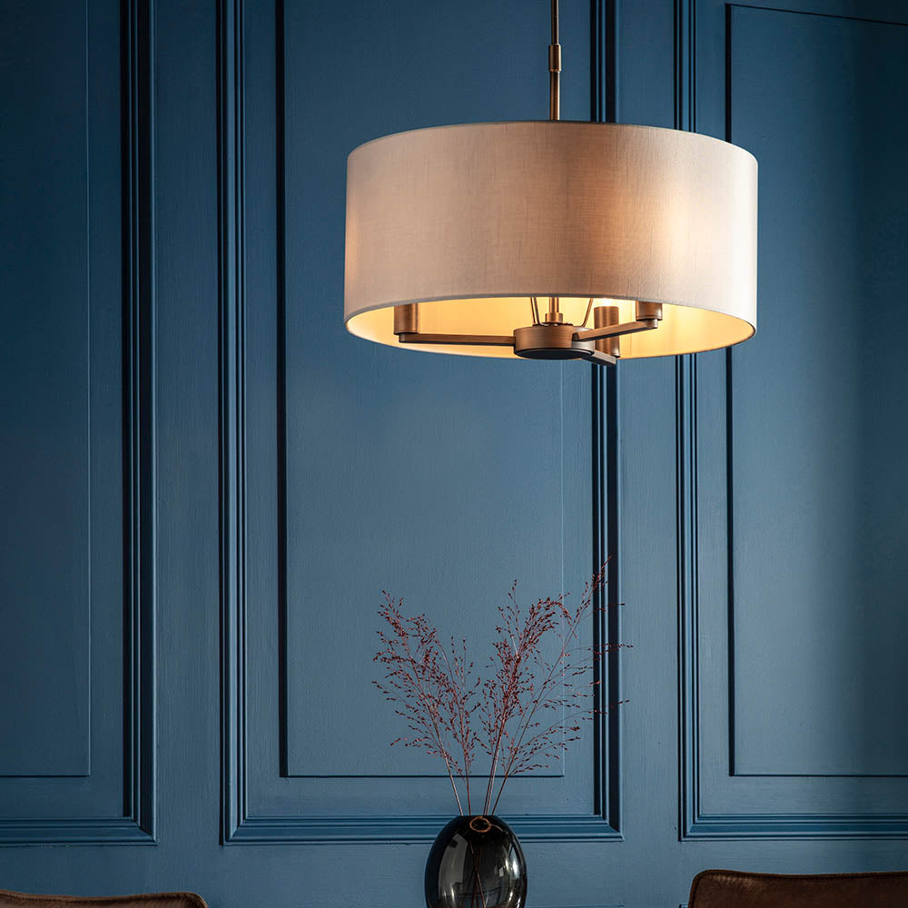 Endon Bexley Large 3 Light Pendant in bronze with marble-effect faux silk drum shade, lit above a dried stem arrangement against a blue panelled wall.