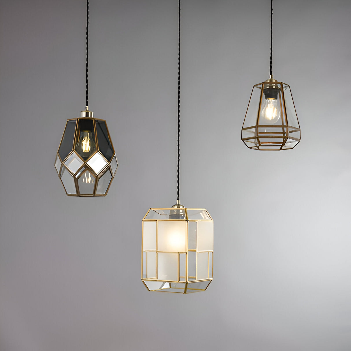 Endon Chartwick pendant shades in antique brass with clear and grey glass panels, shown in three geometric cage shapes hanging against a light grey background.