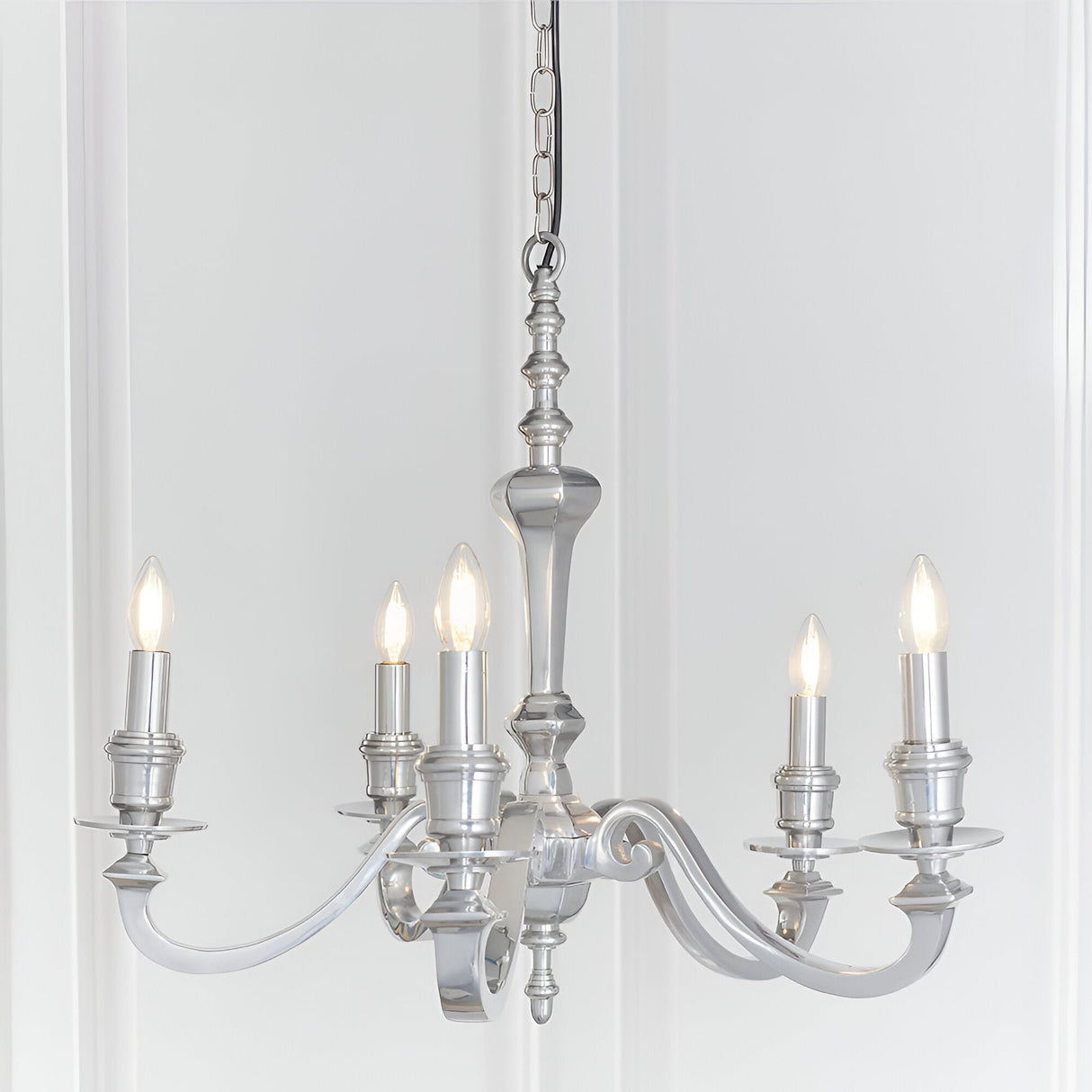 Endon Brambourne 5 light pendant in polished aluminium with curved arms and candle-style lampholders, suspended from a chain against a white panelled wall.