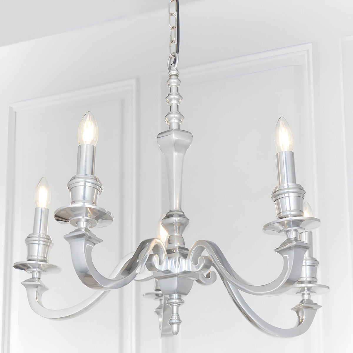 Endon Brambourne 5 light pendant in polished aluminium with curved arms and candle-style lamps, suspended from a chain against white panelled walls.
