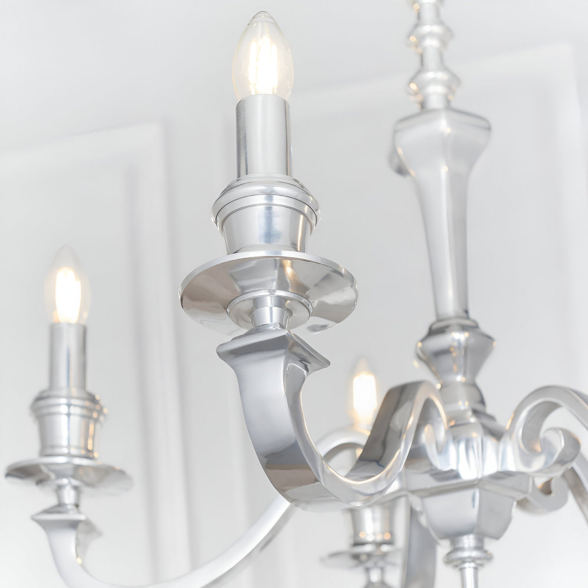 Close-up of the Endon Brambourne 5 Light Pendant in polished aluminium, showing curved arms with candle-style E14 lampholders against a white ceiling.