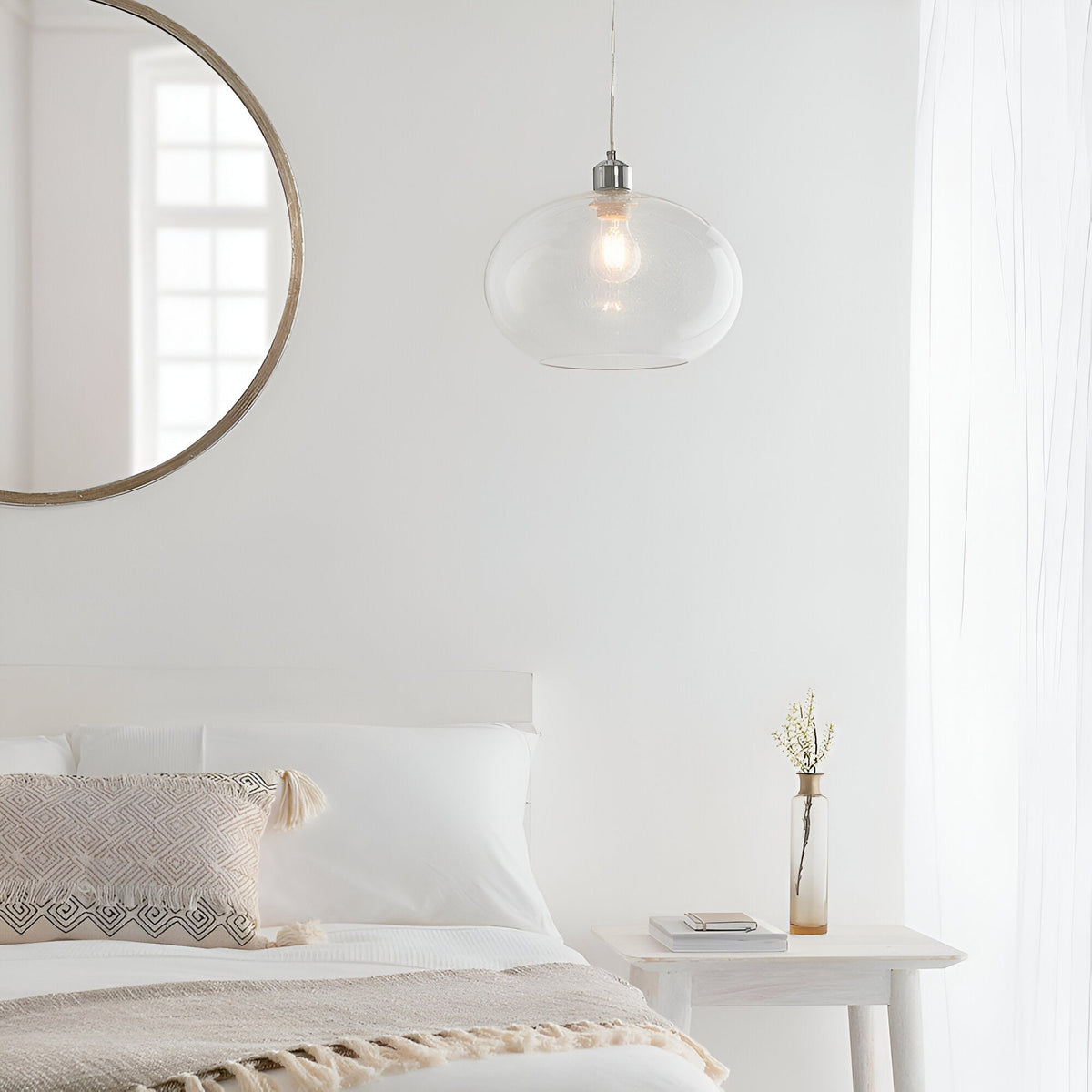 Endon Brackcombe clear bubble glass pendant shade with chrome fitting, hanging in a white bedroom beside a round wood-framed mirror and bedside table.