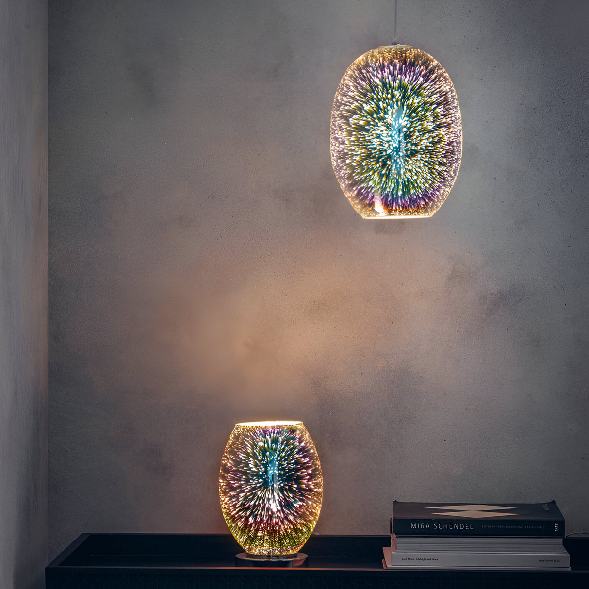 Endon Cliffwick touch table lamp with holographic multicolour glass body on a chrome base, shown lit beside books with a matching pendant above.