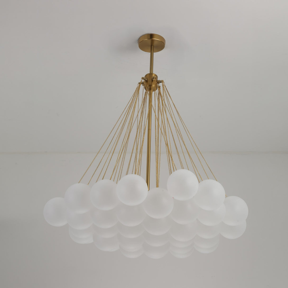 The Orb 37 Light Cluster Suspension - Gold is a modern chandelier with multiple frosted glass globes clustered together, suspended from the ceiling by slim gold cords.