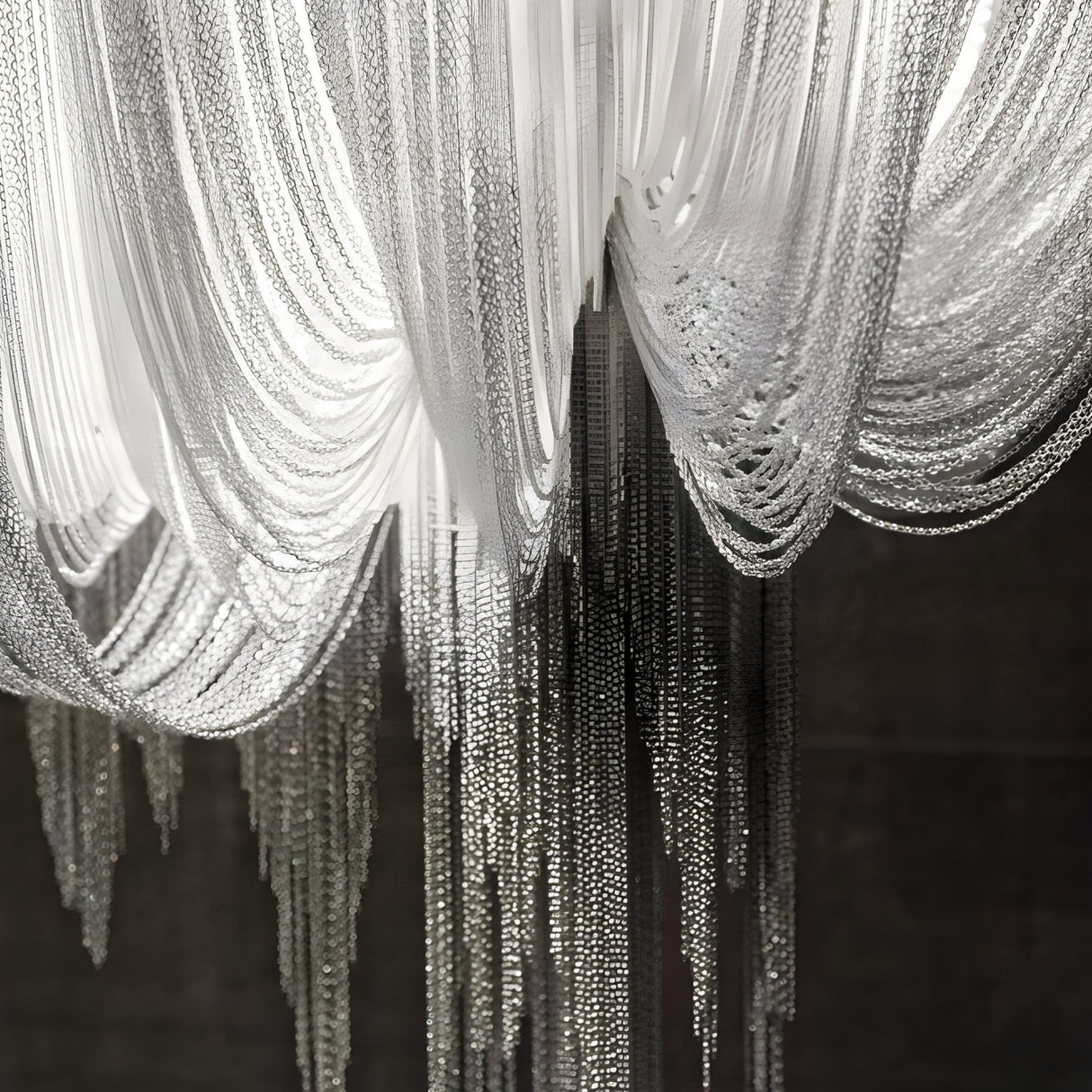 Close-up of the Mireya 8 Light Metal Chain Veil Chandelier in Nickel, featuring layered silver and white chains draped in graceful curves and hanging strands, illuminated against a dark background.