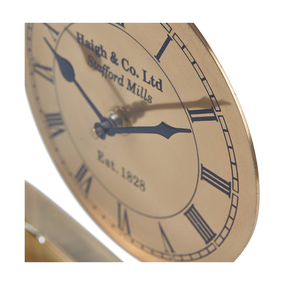 Close-up of the Gold Brass & Glass Floating Clock Face Table Clock, showing Roman numerals, blue hands, and "Haigh & Co. Ltd" text on a gold dial against a white background.