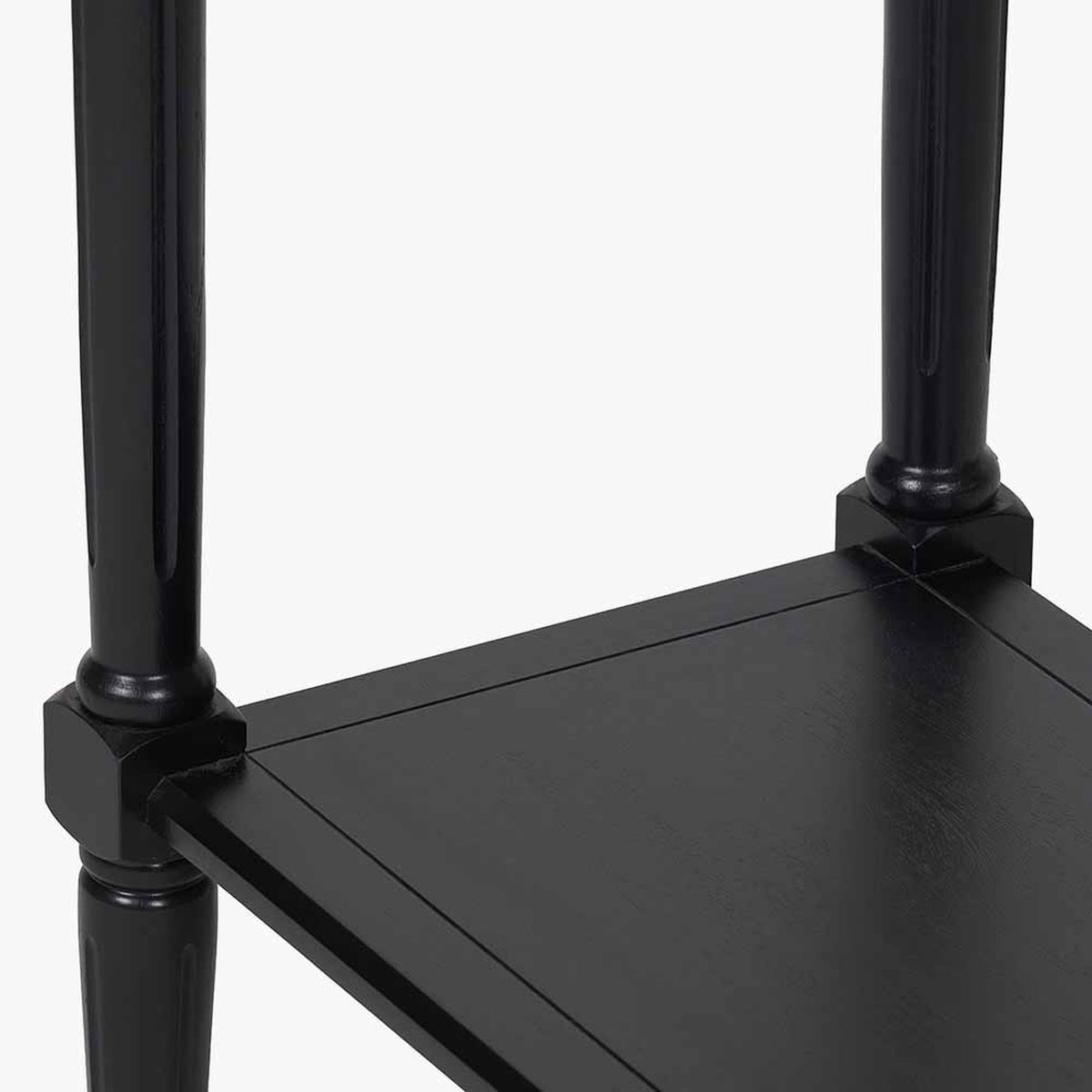 Close-up of the Heritage Black Pine Console Table, 80cm, showing turned black wood legs joining a shelf with visible corner bracket detailing.