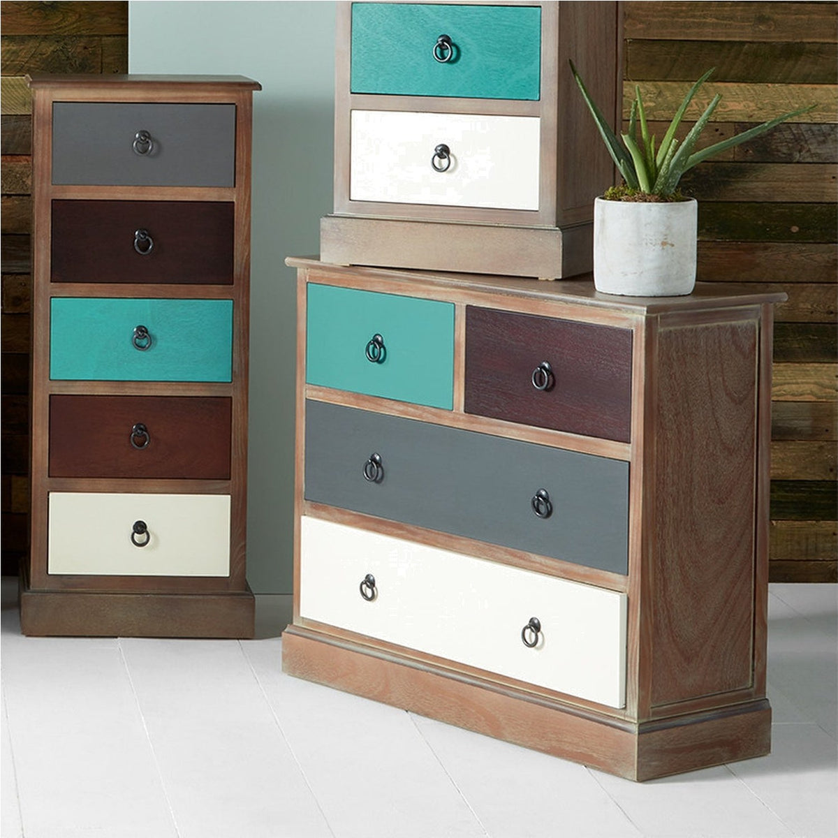 Loft Blue Multicoloured Pine 4 Drawer Unit, 72cm chest of drawers with teal, burgundy, grey and cream drawers and ring handles, shown with a matching tall chest and potted plant.