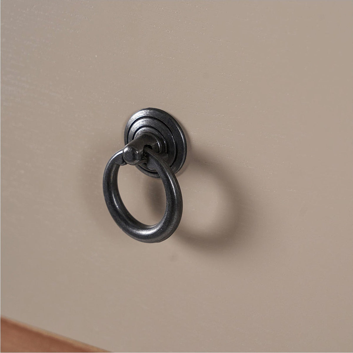 Close-up of a dark metal ring pull handle with round backplate on a sage green drawer front from the Loft Sage chest of drawers.