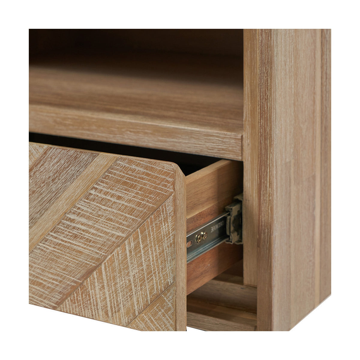 Close-up of the Marca Sand Wash Acacia shelving unit's open drawer with herringbone wood front, metal slide runners, and visible interior shelf in a light sand wash wood finish.