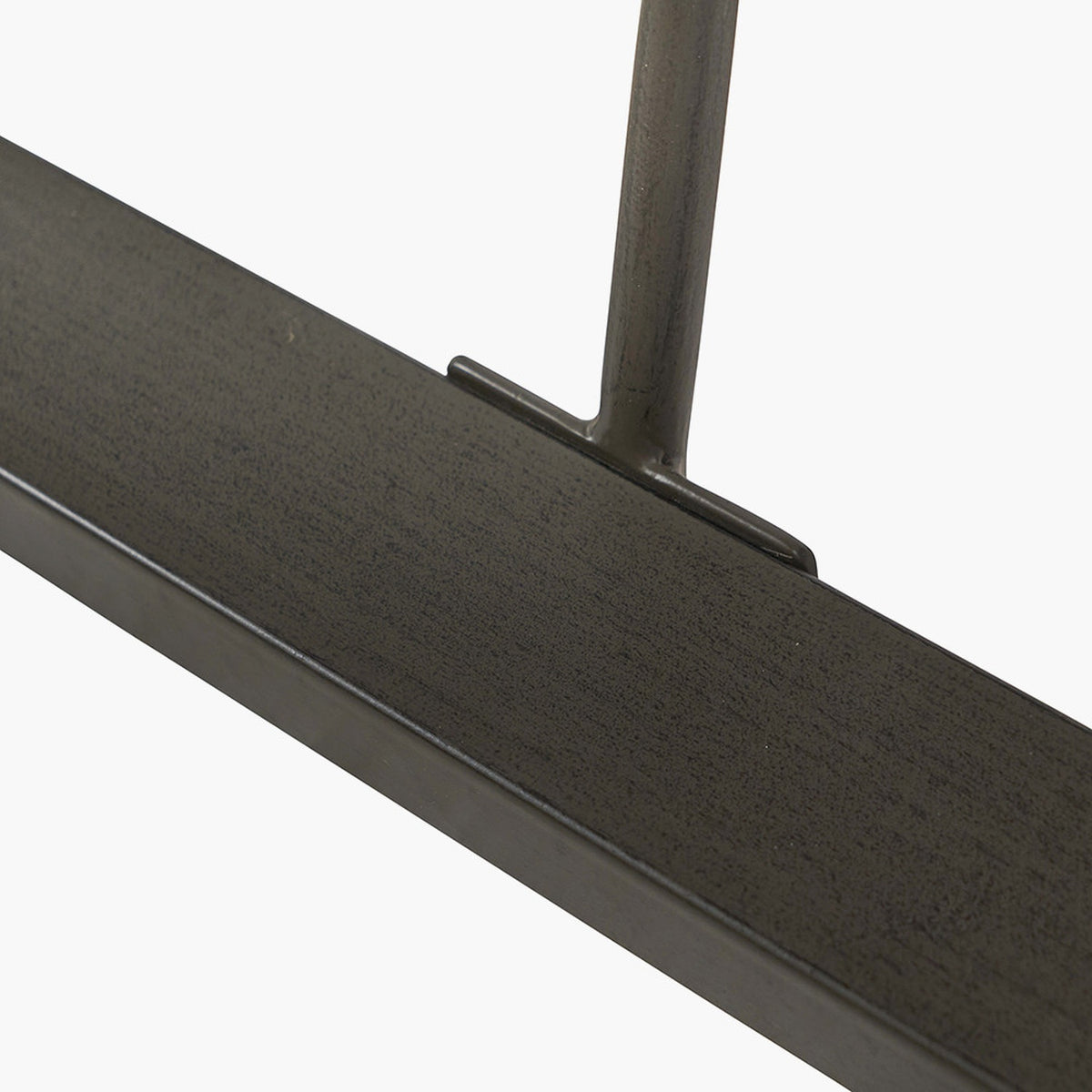 Close-up of the Marca dining table's black iron leg joint against a sand wash acacia wood tabletop edge, shown on a plain white background.