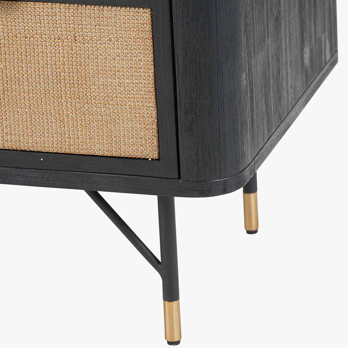 Close-up of the Fiji Black Acacia & Rattan 4 Drawer Unit, showing black wood corner detailing, a woven rattan drawer front, and angled metal legs with brass-tone feet.