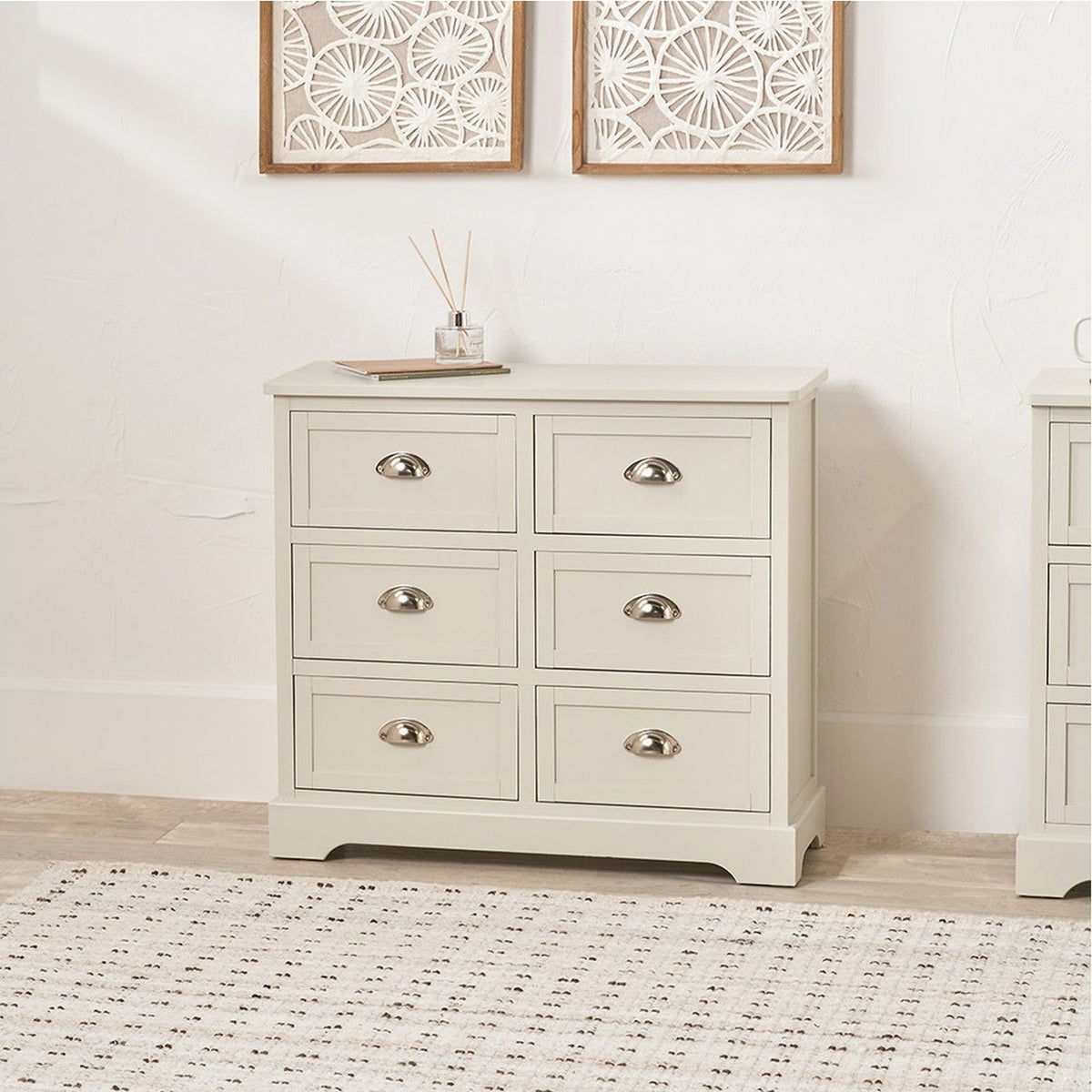 Croft Linen Pine 6 drawer unit chest of drawers with cup handles in a pale finish, shown in a bedroom setting beside wall art.