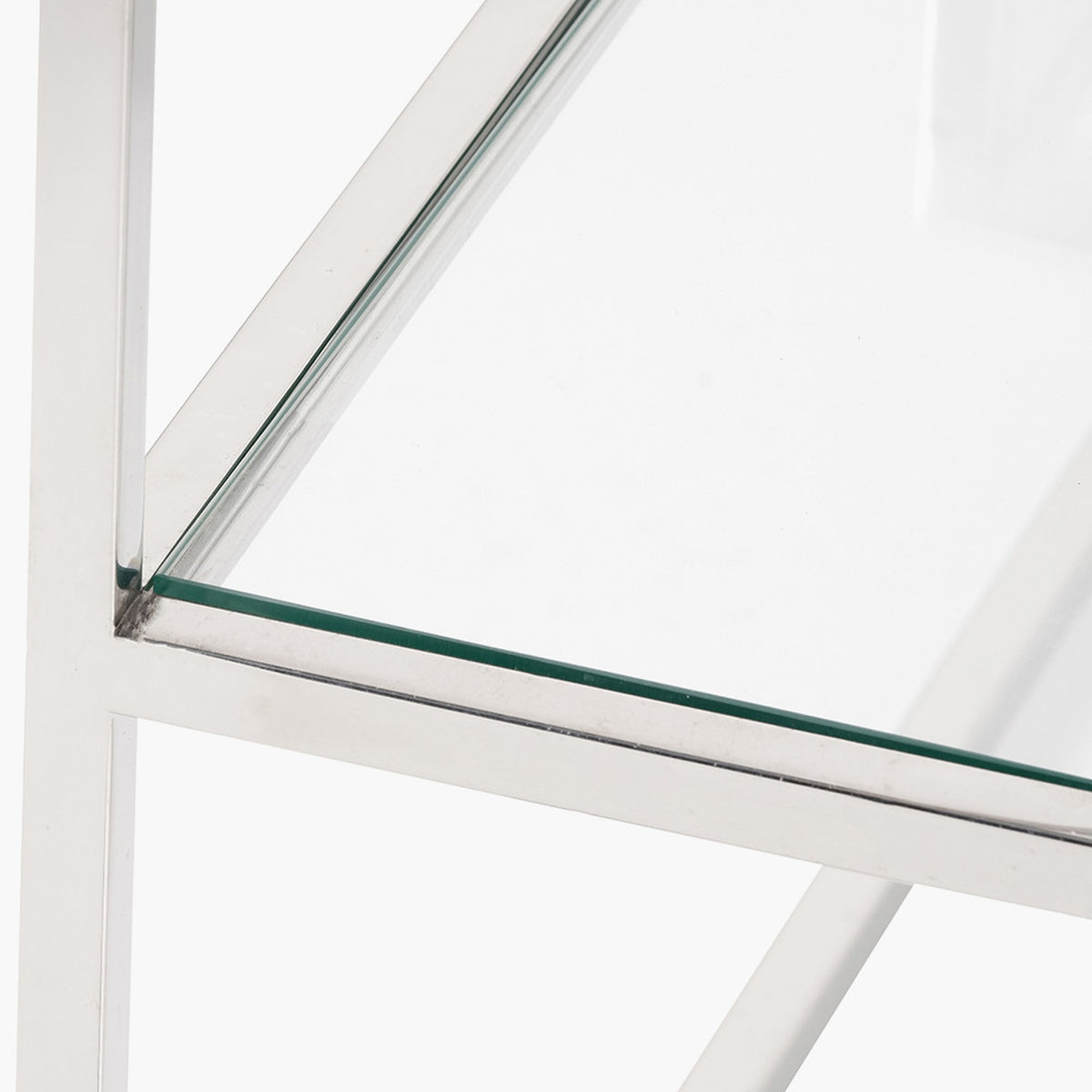 Close-up of the Aleandra console table's chrome metal frame corner joint with clear glass shelf, shown against a plain white background.