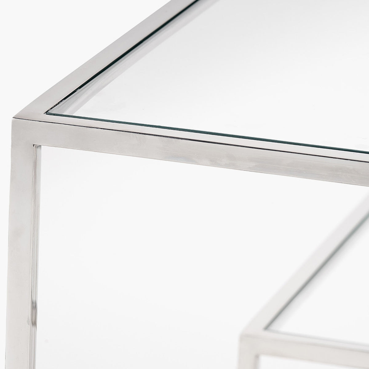 Close-up of the Aleandra console table's corner joint, showing clear glass top and chrome metal frame on a plain white background.
