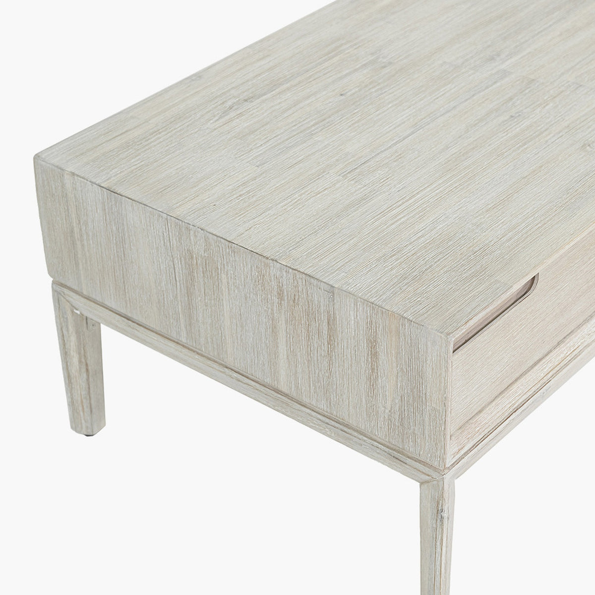 Close-up of the Gio White Sand Acacia 2 Drawer Coffee Table corner, showing white-washed wood grain, tapered leg, and recessed drawer handle on a plain background.