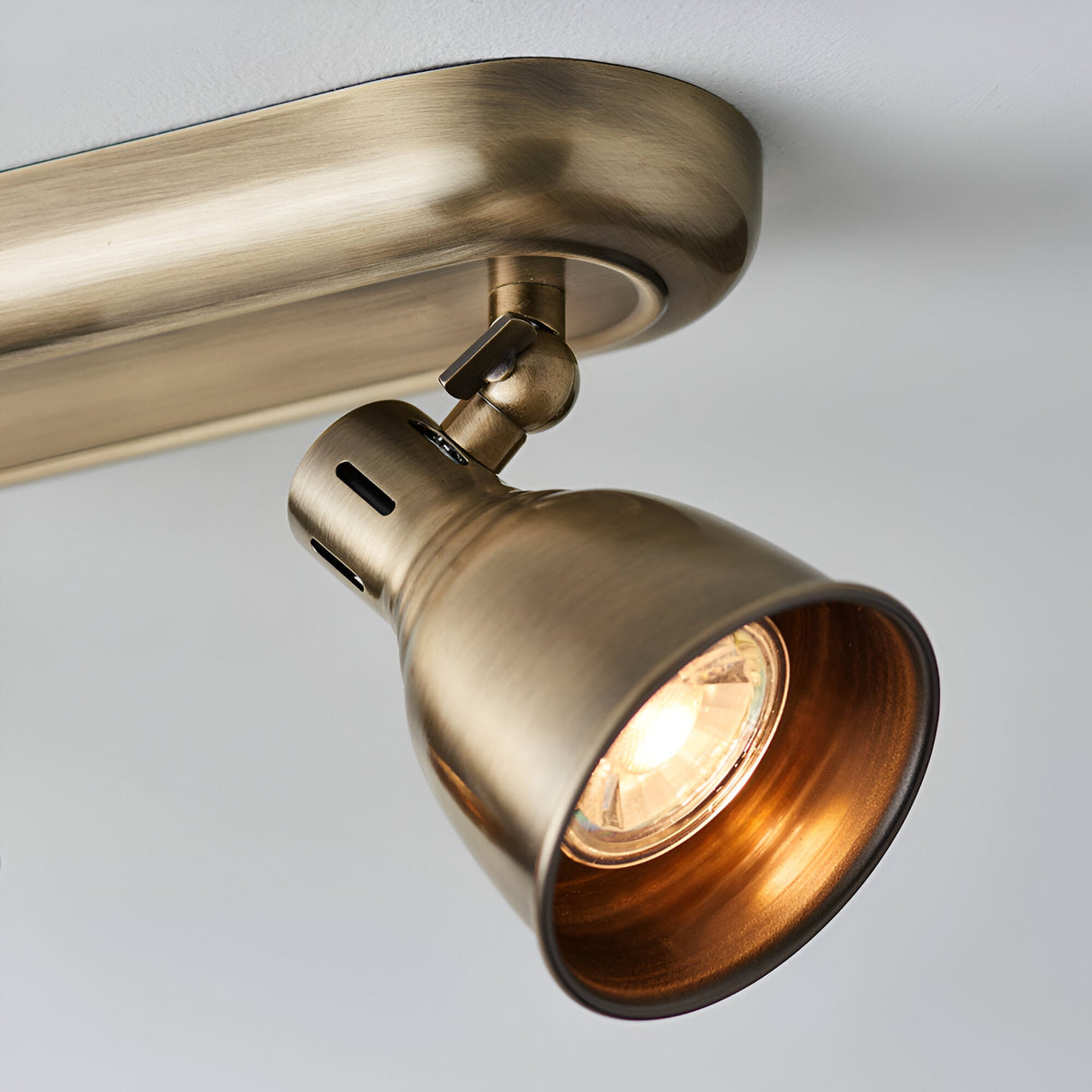 Close-up of Endon Daneford spotlight showing one adjustable antique brass head with visible bulb, mounted on a ceiling plate against a white background.