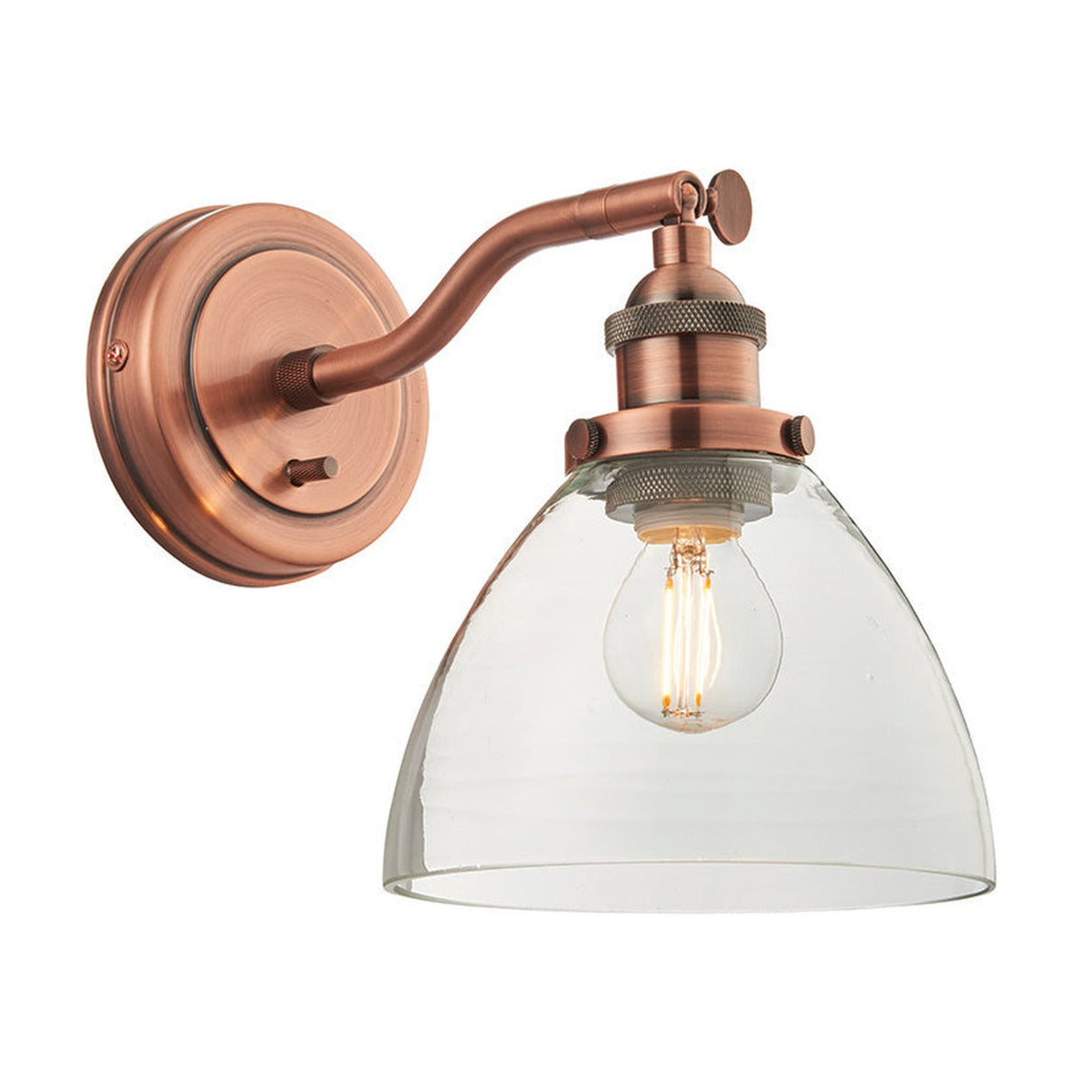 Endon Wentworth wall light in copper with adjustable knuckle, toggle switch and clear glass dome shade over a lit E14 filament bulb, on white.