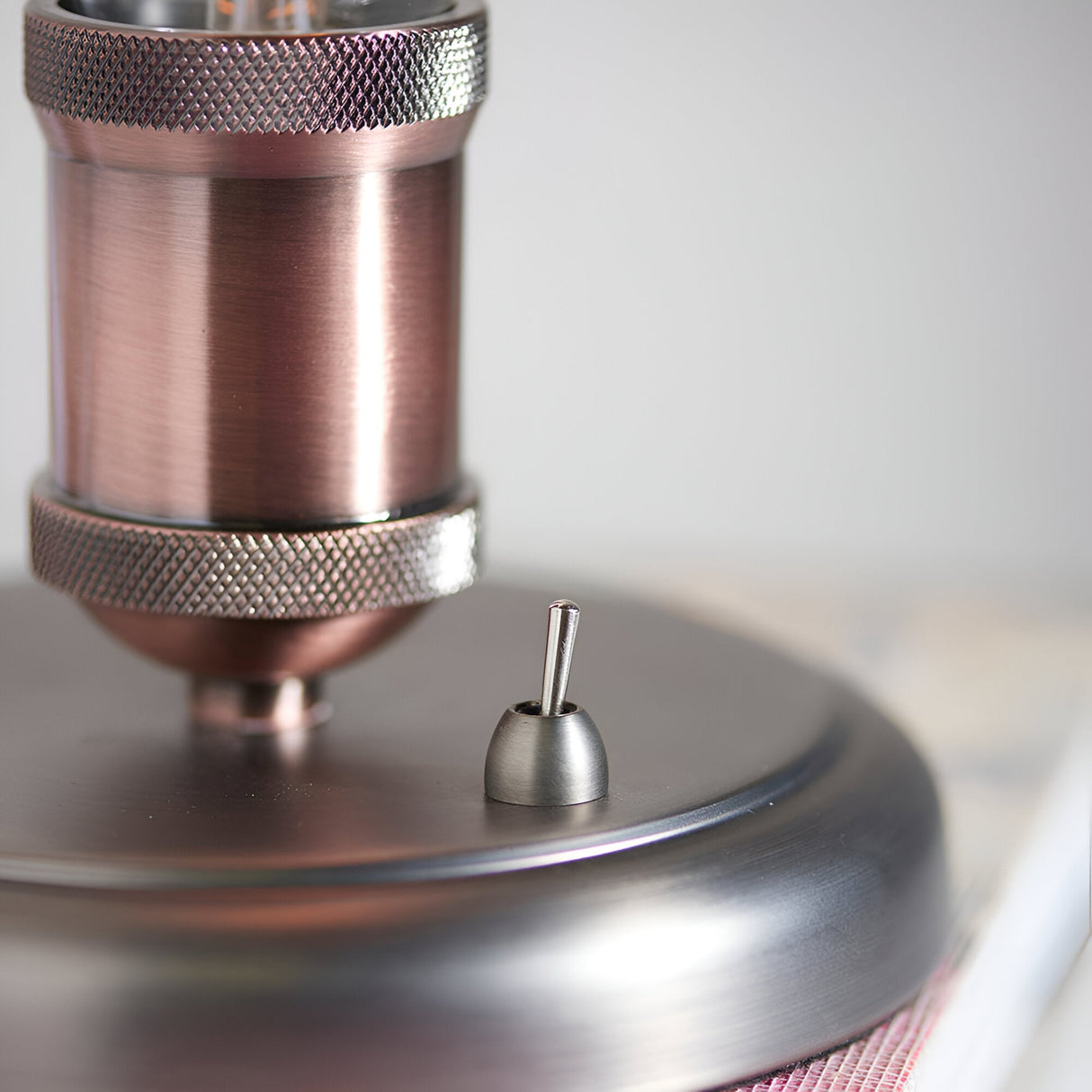 Close-up of Endon Brackley table lamp base showing aged copper cylindrical holder with knurled detailing and pewter toggle switch on brushed metal base.