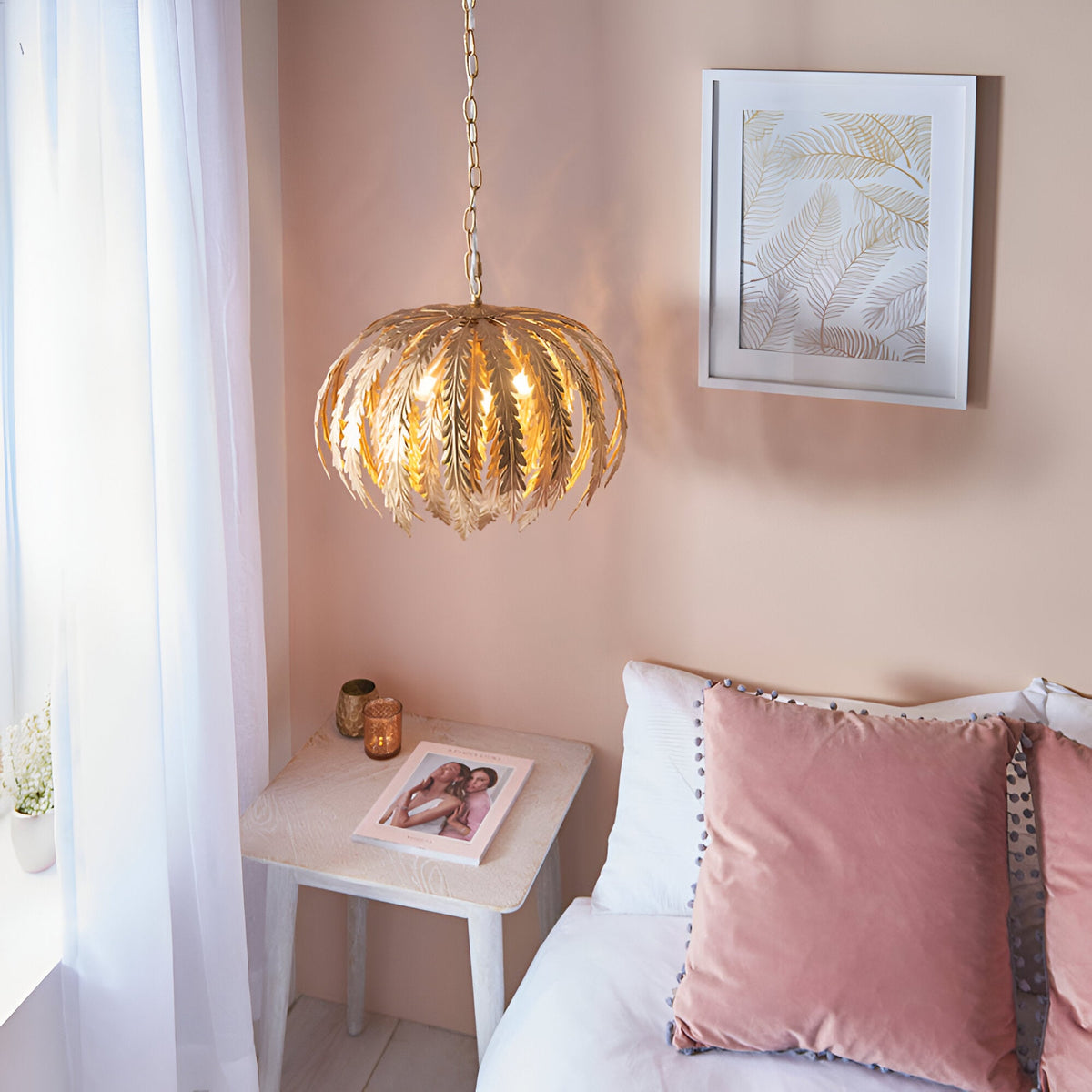 Endon Colette 3 light pendant in gold leaf with layered floral leaf shades, hanging on a chain above a bedside table in a soft pink bedroom.