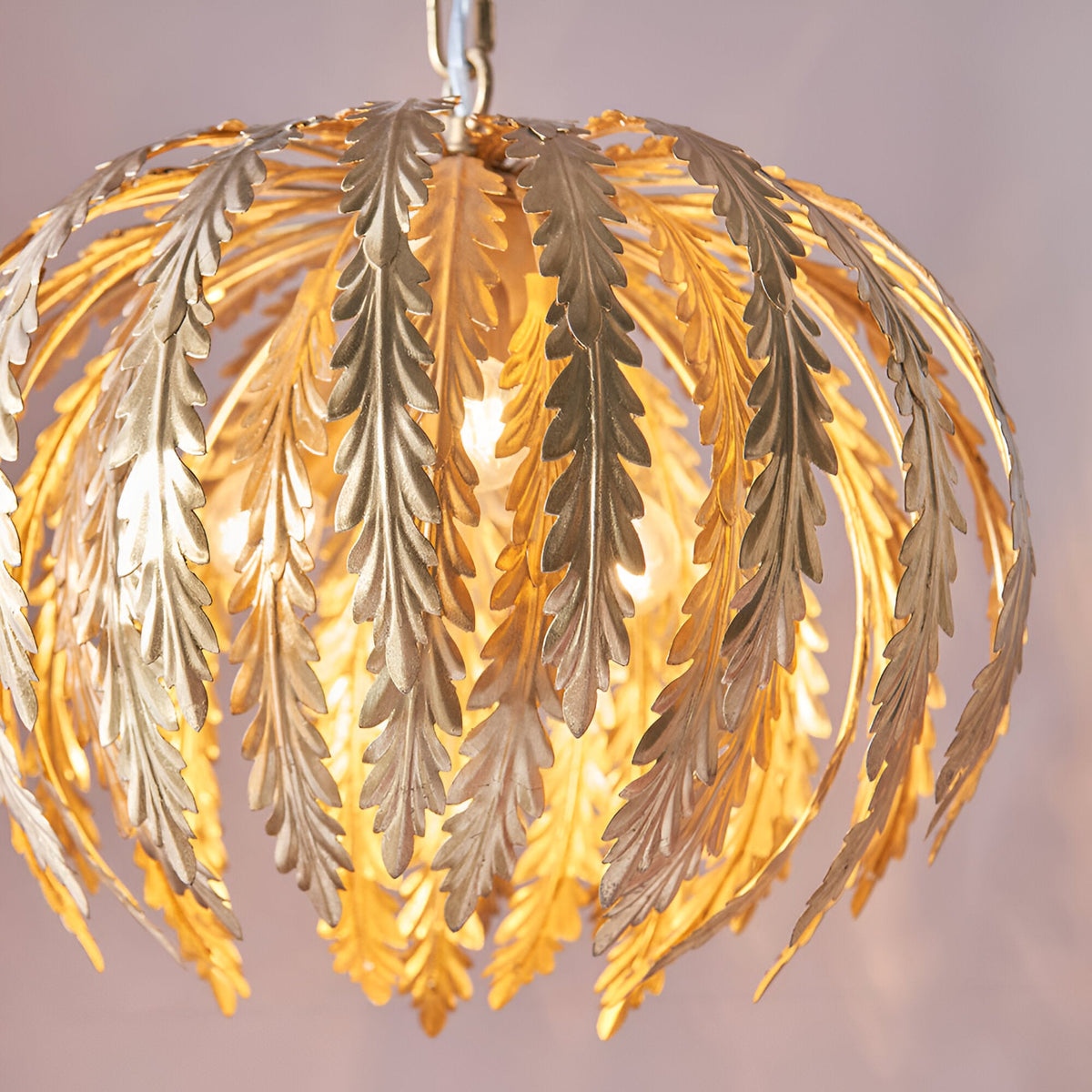 Endon Colette 3 light pendant with layered gold leaf fronds fanning over illuminated bulbs, suspended from a chain against a soft neutral background.