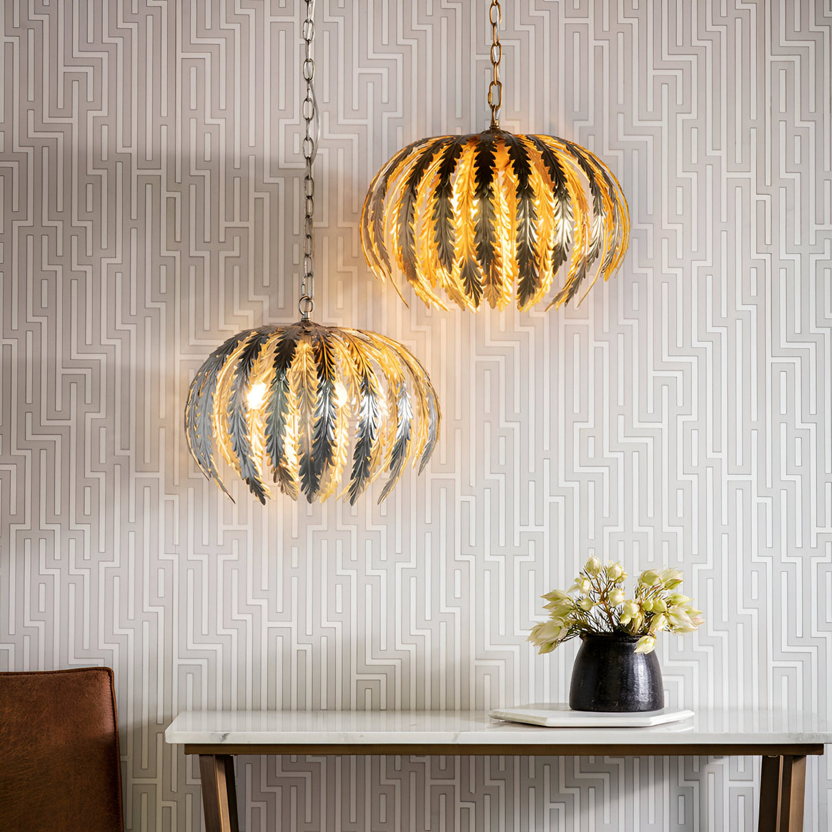 Endon Colette 3 light pendants in gold leaf with layered floral leaf shades, hanging on chains above a marble console in a patterned wallpaper interior.