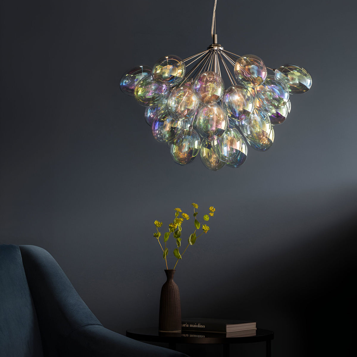 Endon Brenworth 6 light pendant with clustered iridescent glass globes on a chrome frame, hanging in a dark blue room above a vase of yellow flowers.