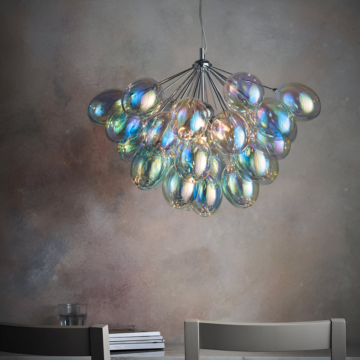 Endon Brenworth 6 light pendant in chrome with clustered iridescent glass shades, suspended above a dining setting against a textured grey wall.