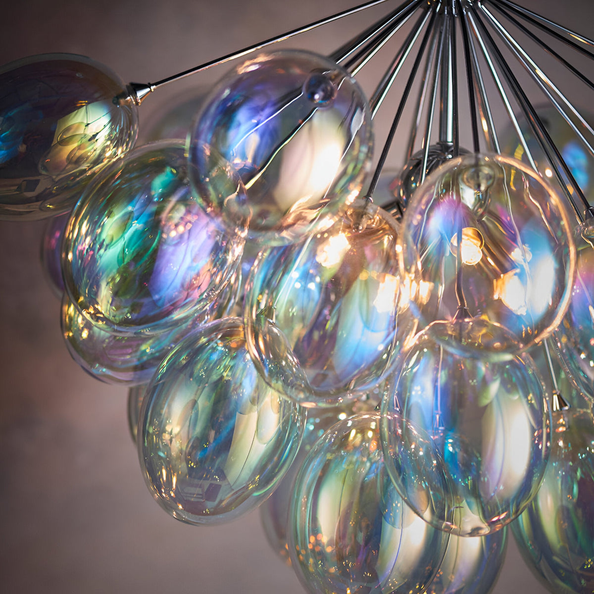 Close-up of Endon Brenworth 6 Light Pendant showing clustered iridescent glass shades in blue, green and amber tones suspended from chrome rods.