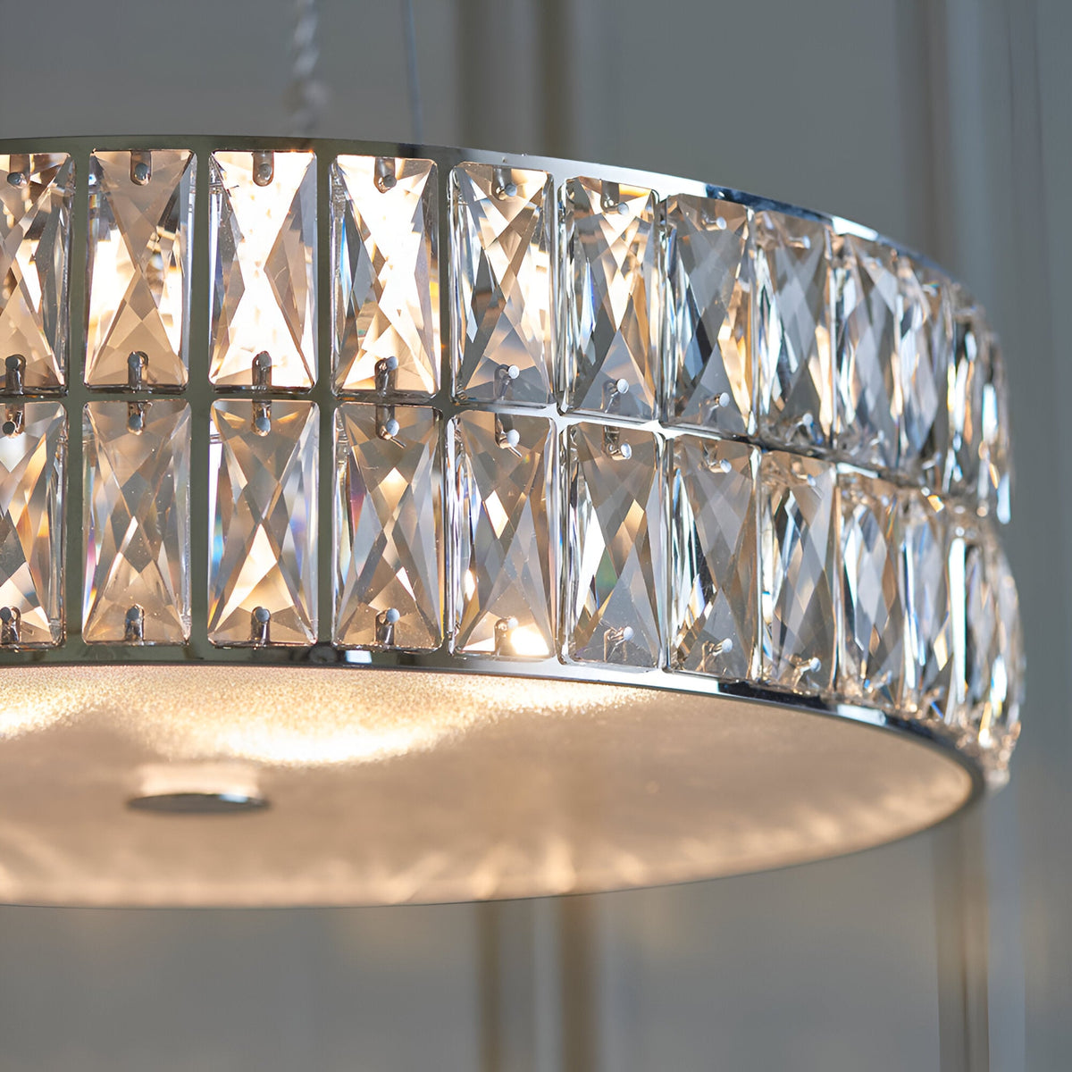 Close-up of the Marguerite LED Round Pendant in chrome, showing two tiers of faceted crystal panels around a glowing frosted glass diffuser.