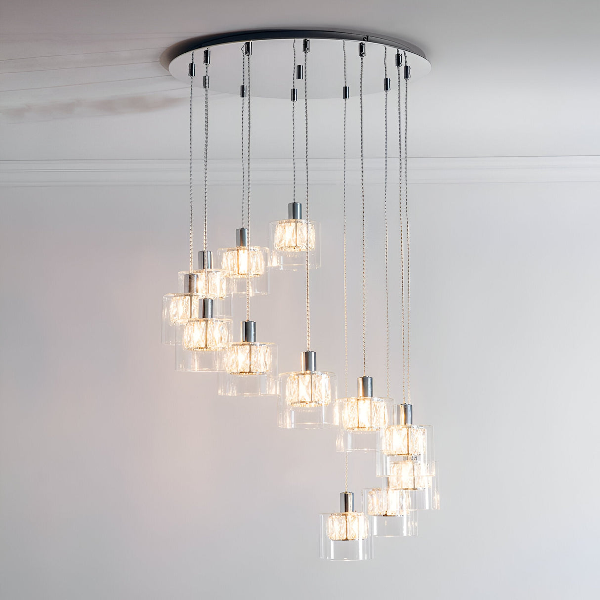 Marguerite 12-light pendant in polished chrome with cylindrical clear glass shades, cascading at staggered heights from a round ceiling plate.