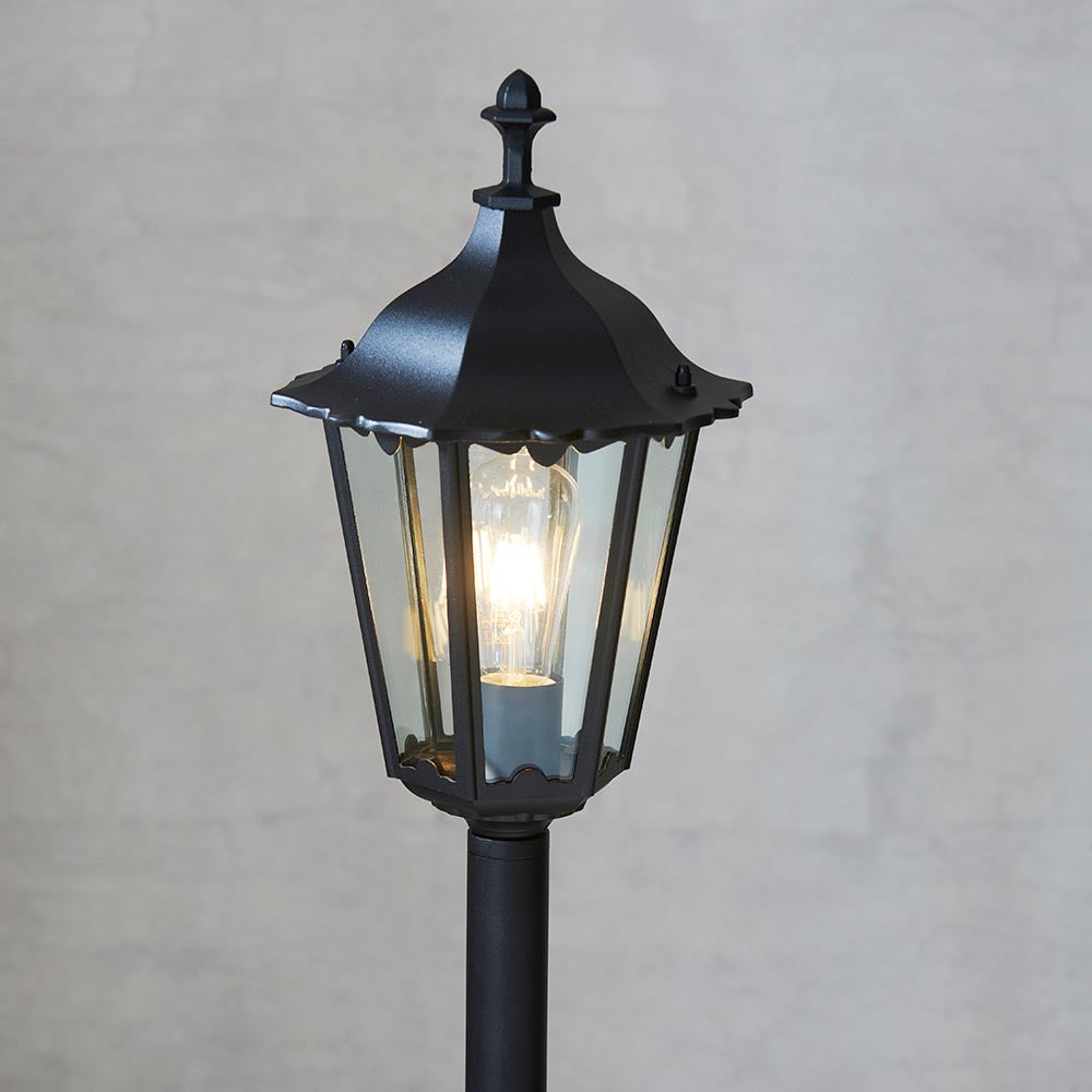 Endon Ashshaw bollard light in matt black die cast aluminium with a traditional lantern head, clear glass panels and a visible E27 filament bulb.