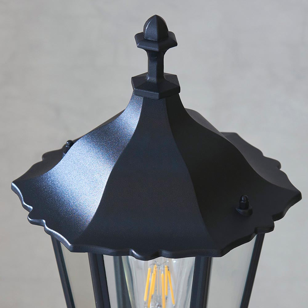 Close-up of the Endon Ashshaw bollard light in matt black die cast aluminium, showing the lantern top, decorative finial and filament bulb behind clear glass.