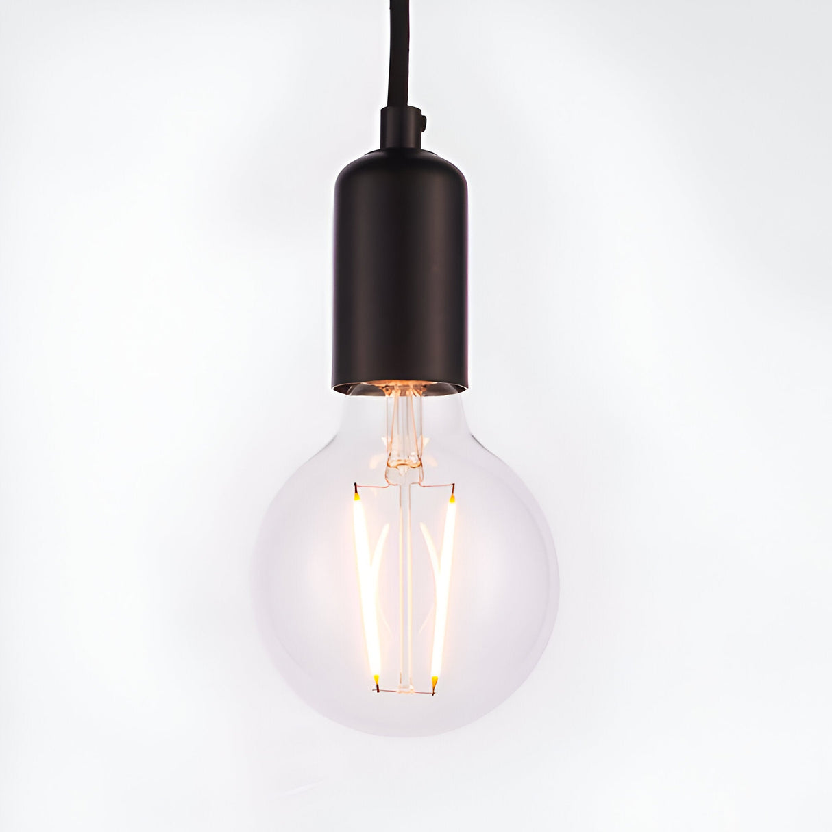 Endon Marlowe pendant light with a matt black E27 lamp holder on black fabric flex, fitted with a clear globe filament LED bulb, on white.