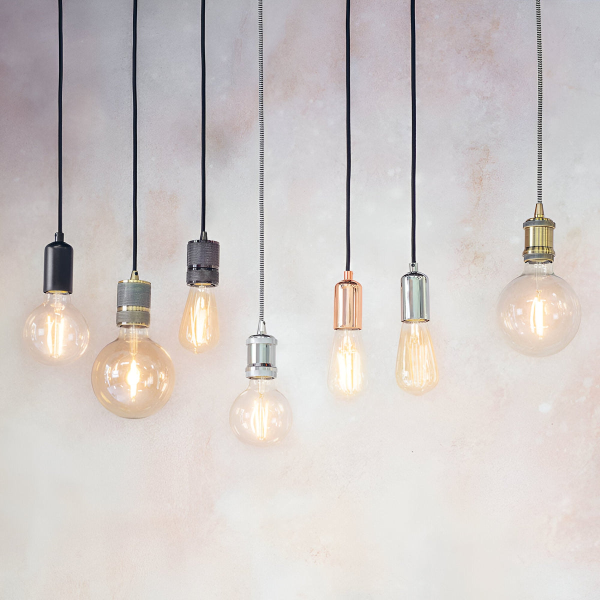 Endon Camden pendant lights in chrome, black, brass and copper finishes with exposed filament E27 bulbs on black flex cables against a light background.