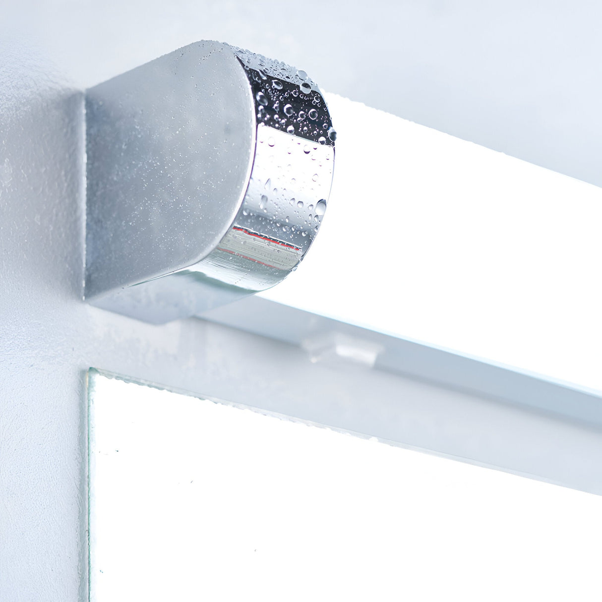 Close-up of the Endon Carlshaw LED bathroom wall light, showing the chrome cylindrical end cap and white ribbed diffuser mounted above a mirror.