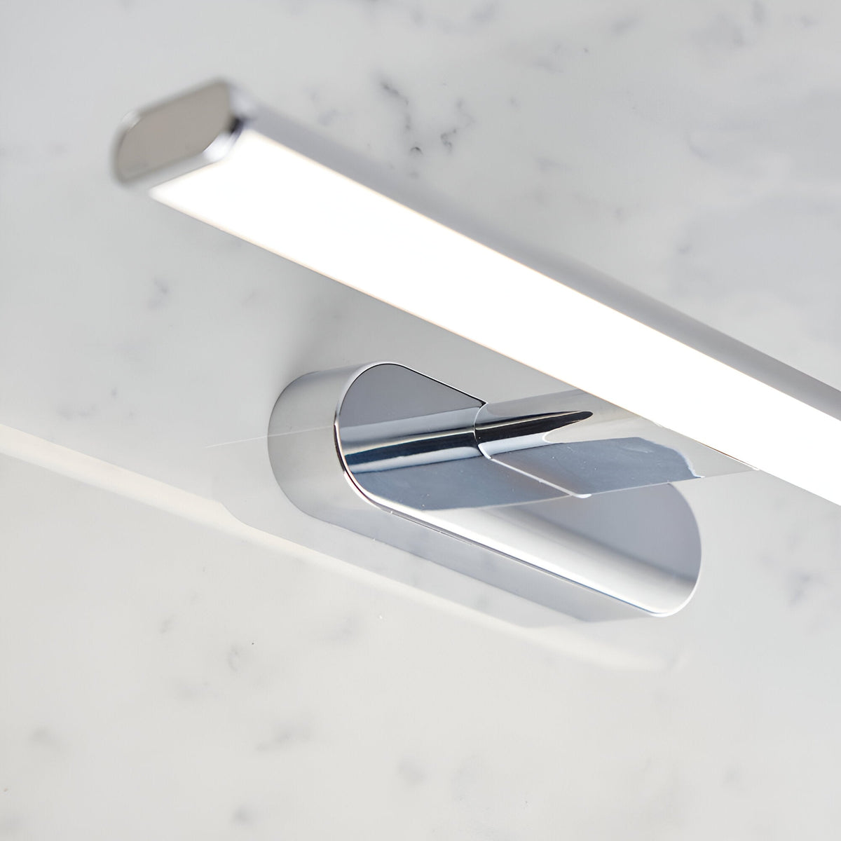 Carlshaw LED bathroom wall light in chrome, with an elongated frosted opal diffuser mounted above a marble surface.
