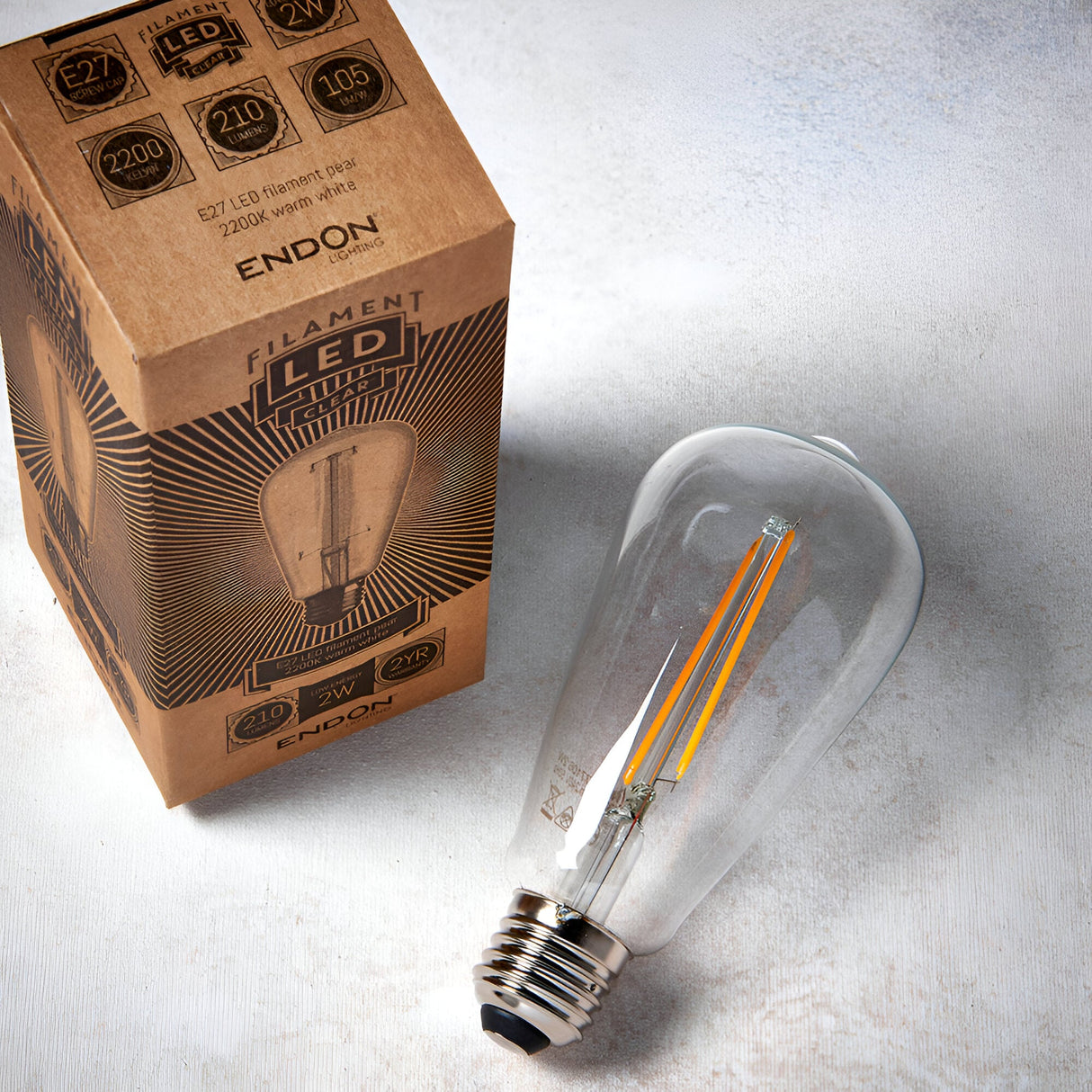 Endon 2W E27 LED filament pear bulb in clear glass with warm white filament, shown beside its printed kraft box on a light background.