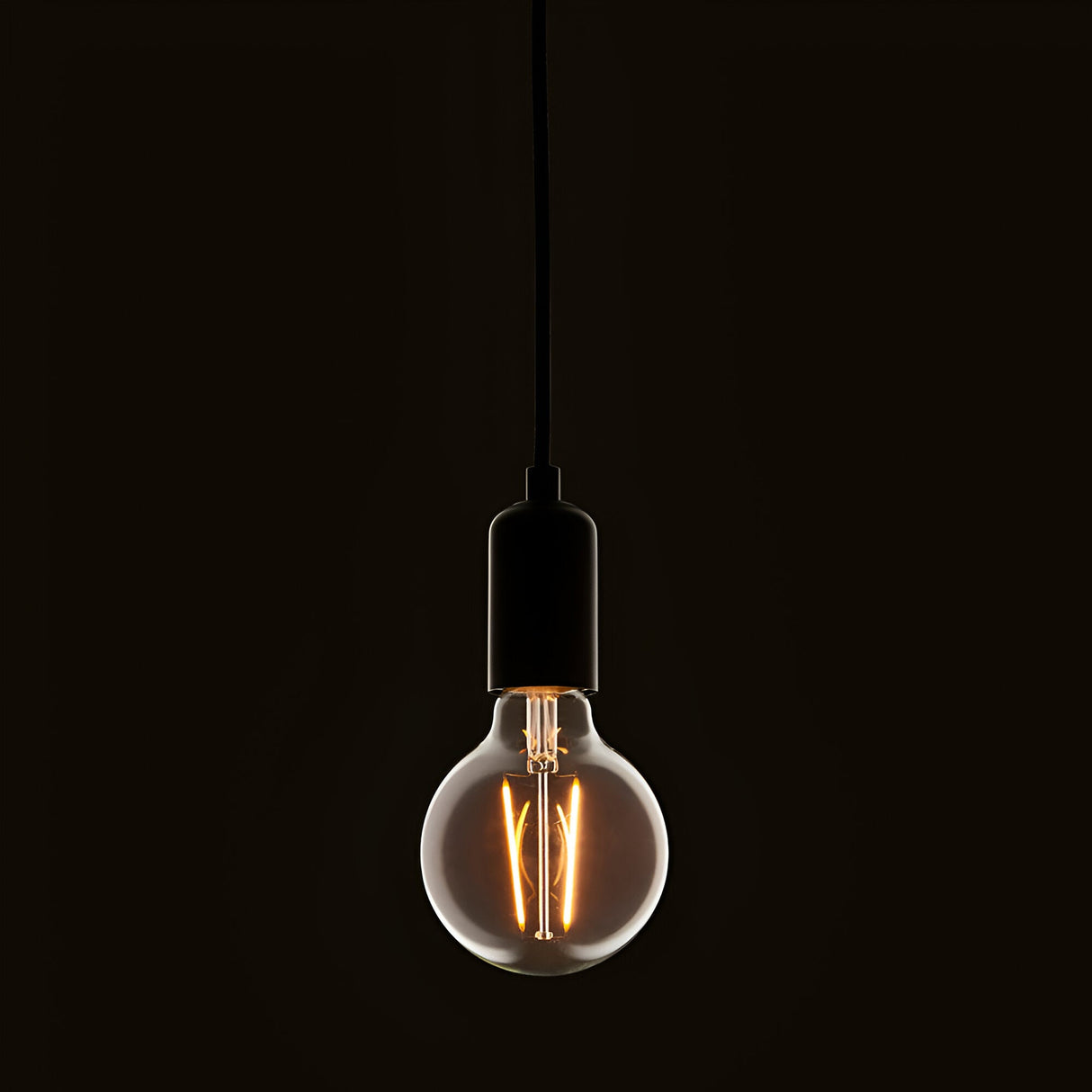 Pendant light fitted with a clear E27 LED filament globe bulb, glowing warm white against a dark background.