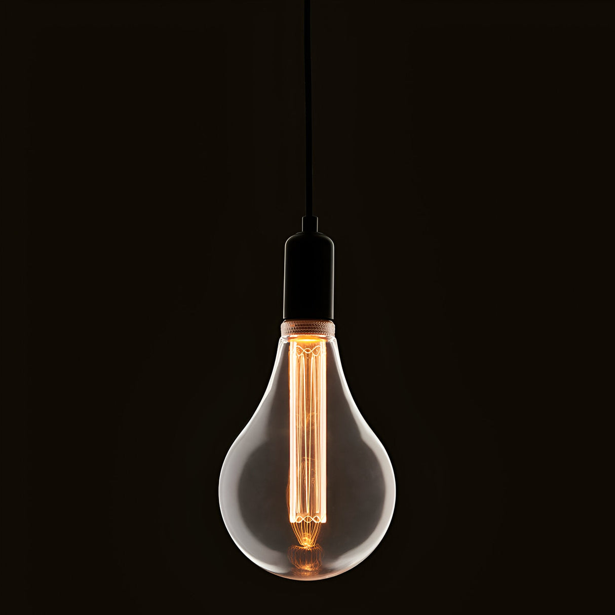 Pendant light with clear oversized E27 LED globe bulb, warm white glowing filament, black cord and fitting, dark background.